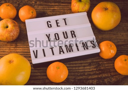 get your vitamins concept: lightbox with message surrounded by healthy oranges grapefruits and apples