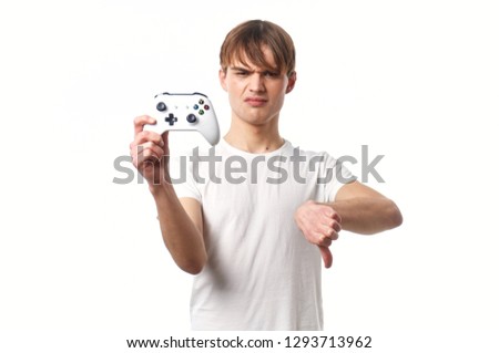 A handsome man with a joystick from the set-top box in his hand shows down his thumb                            