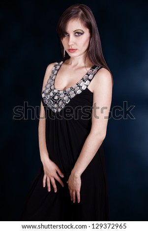 Portrait attractive brunette in black dress. Fashion studio shot