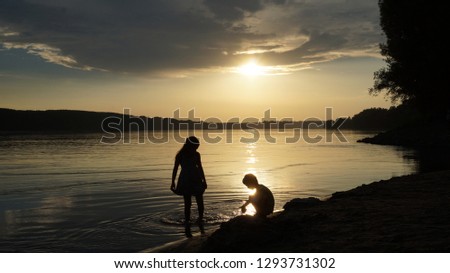 children play on a sandy beach as the sun sets