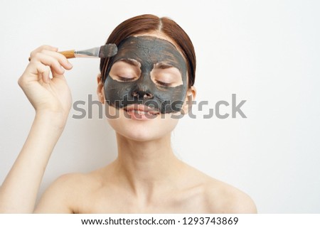 young woman applies cosmetic mask on face smiling