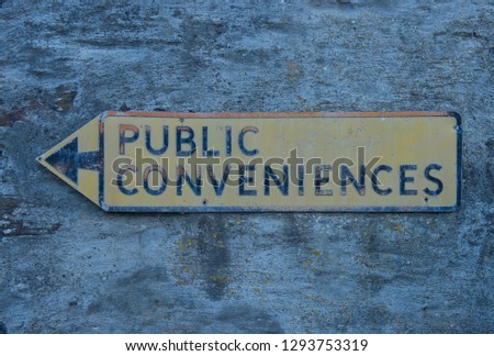 Faded "Public Conveniences" Sign Attached to a Stone Wall in the Seaside Village of Port Isaac in Rural Cornwall, England, UK