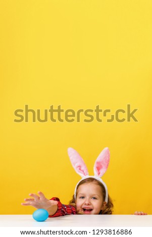 Cute little child girl with bunny ears at home is hunting for Easter eggs.