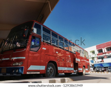The red bus is parking in the bus station against blue sky