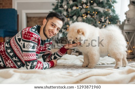Portrait of beautiful young man with the dog чаучау in Christmas sceneries