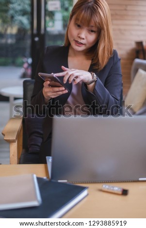 A portrait of businesswoman pressing on phone. She is sitting in office. This picture can be used in such concept as making phone call, financial, business, investment, working woman, communication.  