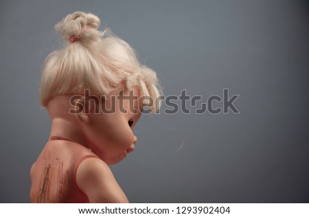 The doll with full writing on the back represents the child being bullied.scared and alone baby doll.selective focus on back.