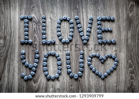 Ripe tasty blueberries and berries on a wooden table with I love you words