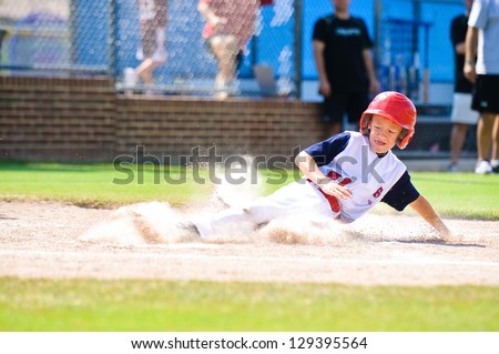 Youth baseball player sliding in at home.