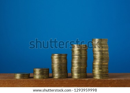 Stacks of metal coins on a blue background, close-up