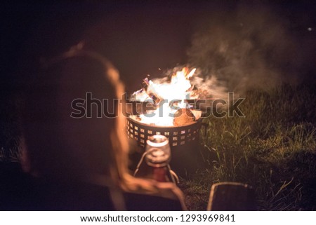 a woman with long hair enjoys wine and a warm outside fire