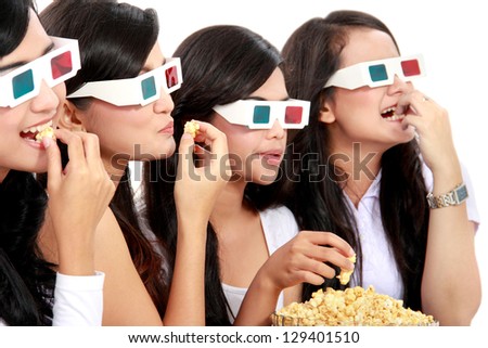 Group of girls watching the movie wear 3D glasses while eating popcorn