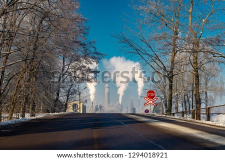 View down a winter street of smoking chimney stacks in an industrial district in a concept of pollution of the atmosphere