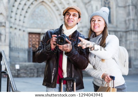 Portrait of adult travelers male and female standing with camera at street
