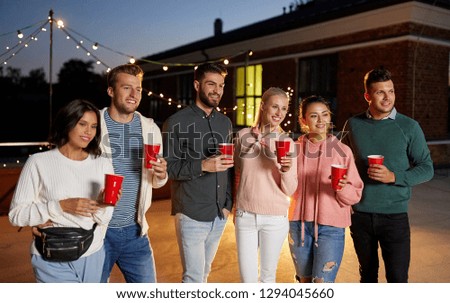 leisure, celebration and people concept - happy friends with drinks at rooftop party at night