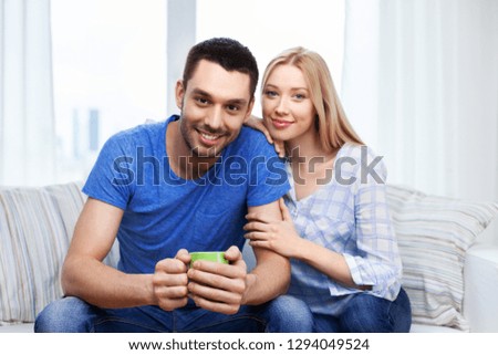 love, family and people concept - happy smiling couple sitting on sofa at home