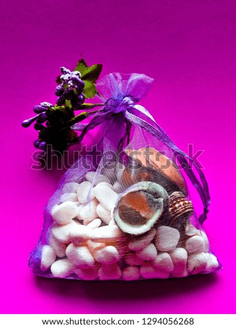 Purple decoration bag with lavanda sea shells on pink background