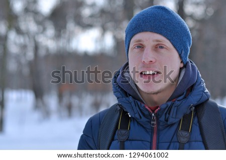 Portrait of a young man photographer in a jacket and hat on the background of winter
