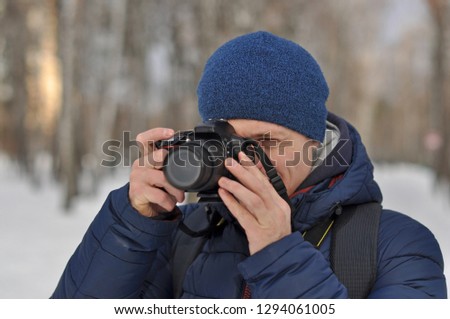 A young man takes pictures in the Park in winter
