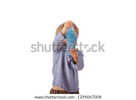Cute small boy holding a blue glitter slime in front of his face. Isolated on white background