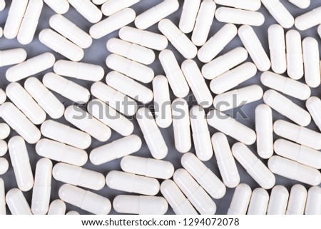 Many white capsules on gray background. Top view. Health care concept,