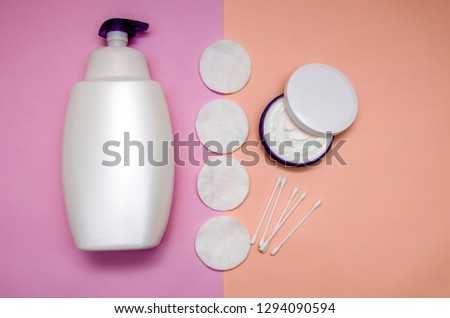 lotion, cotton swabs, cotton disks and cream in a jar. Products for body care and personal care on a pink pastel background. View from above. The trend of minimalism. Flat lay