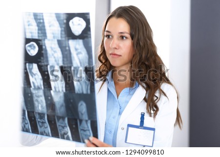 Doctor woman examining x-ray picture while standing near window in hospital. Surgeon or orthopedist at work. Medicine and healthcare concept