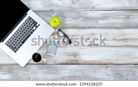 Overhead view of working desktop and smart phone, coffee, reading glasses and green apple with plenty of copy space 