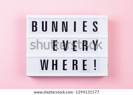 Light box over the pastel background with the text Bunnies everywhere. Easter celebration concept