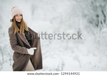 Portrait of blonde woman in hat on walk in winter forest
