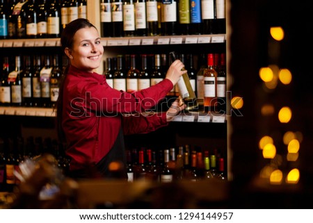 Picture of smiling woman with bottle in her hands in wine shop