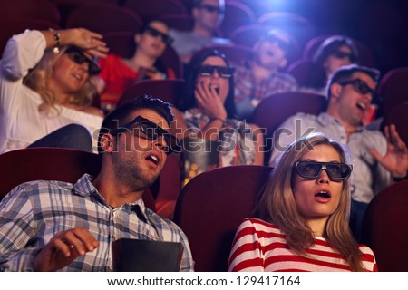 Audience watching 3D horror movie in cinema.