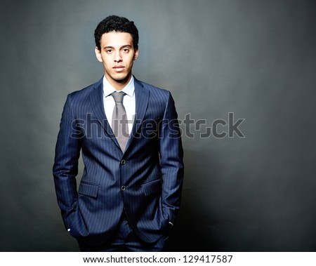Portrait of confident man in suit looking at camera over grey background