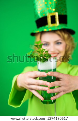 Saint Patrick's Day. Woman in green top hat holds glass with beer. Green beer. Green hat with clover. Irish Traditions. Leprechaun costume. Selective focus.