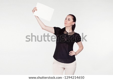 Beautiful young smiling brunette businesswoman holds in her hands a white sheet of paper on an isolated background. Clothes - office style.