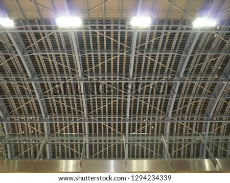 Architectural ceiling pattern with steel columns truss and bracing exposing arches and structural detail in London, United Kingdom.