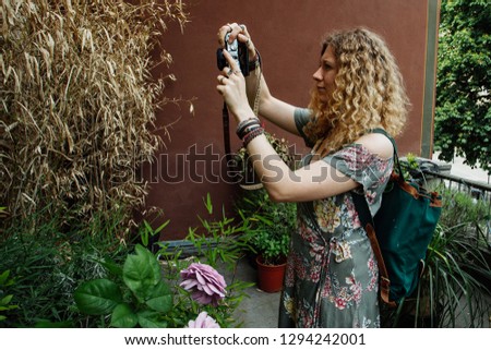 Beautiful young woman with wavy hair in garden with roses
