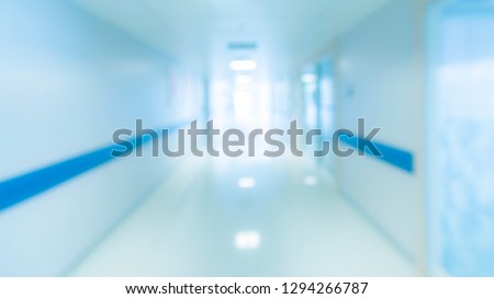 Blurry photo of hospital walk way with bright clean blue lighting. White floor with cool tone color with light tunnel in the middle of picture Use for background purpose.Medical and insurance concept.