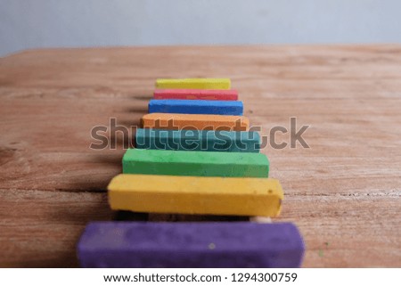 
colorful ladder made of chalk with paintbrush.Wood background.