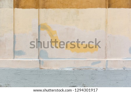 Texture of a wall painted in different colors. Yellow and beige spots on a rough surface. Perfect for background and design.