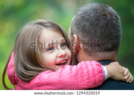 Happy Father's Day. I love you, daddy! Child kissing and hugging dad. Father and little cute daughter playing together in park. Green background. Concept of friendly family