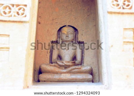 The stone sculpture of Lord Mahavir Jain sitting on a yoga mudra carved in a jain temple at Jaisalmer, Rajasthan.  Royalty-Free Stock Photo #1294324093