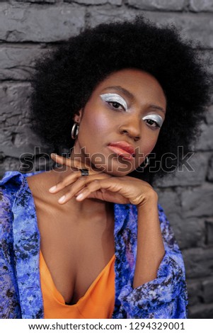 Photo for the fashion magazine. Dark-haired beautiful model with bright makeup looking pretty while posing for the photo