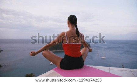 Woman practicing yoga fitness exercise on high place with amazing view of island at sunrise.