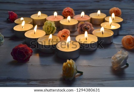 Romantic background: a heart laid out of burning candles and rosebuds.