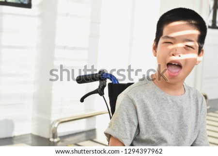 Child on wheelchair is smiling, his face has  light and shadow . Happy disabled child concept.