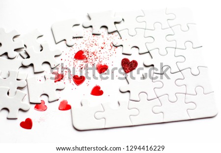 White puzzle with missing parts on white background with red hearts. Love concept. Happy valentines day.