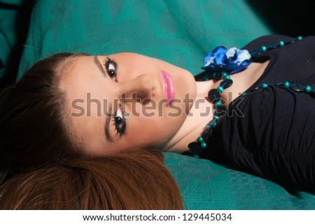Young woman in black dress lying on a sofa.