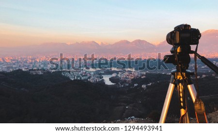 Camera on a Tripod capturing Time Lapse. Sunset over Tirana in the background with clear sky. 