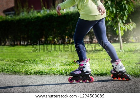Teenage girl is skating on roller skates in the park during summer